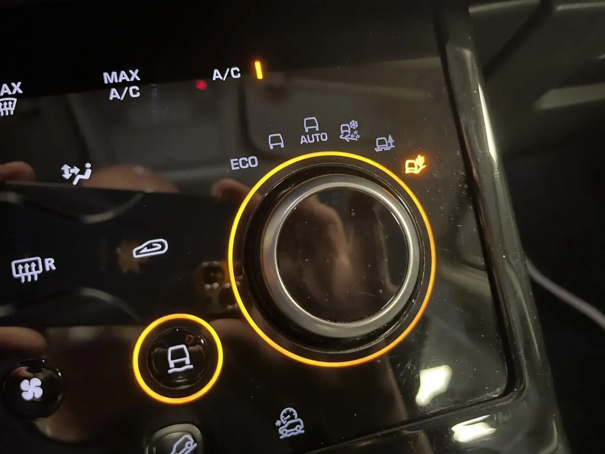 Gros plan sur la commande de modes de conduite du Range Rover Evoque blanc, avec éclairage orange autour du bouton central.