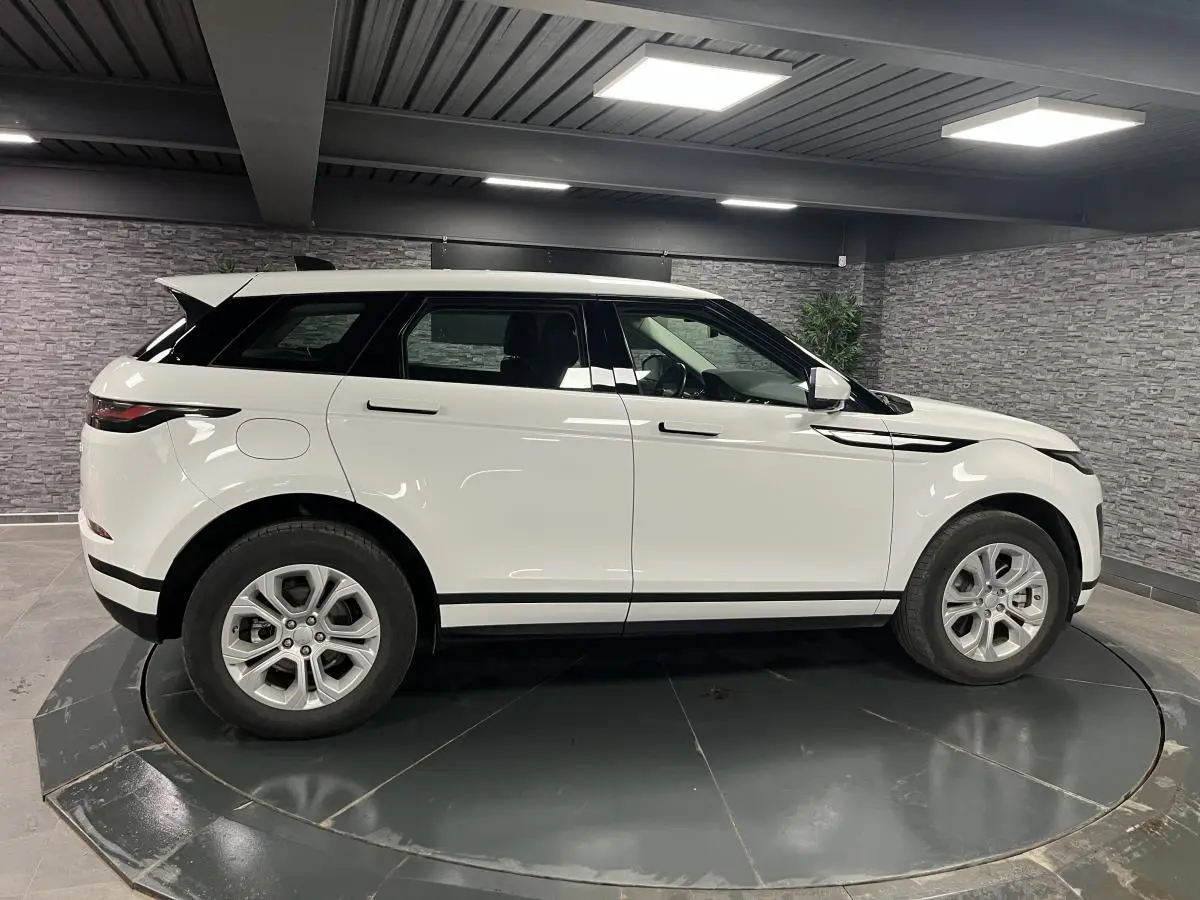 Profil côté gauche d'un Range Rover Evoque blanc 2020 avec jantes 18 pouces dans un garage intérieur.