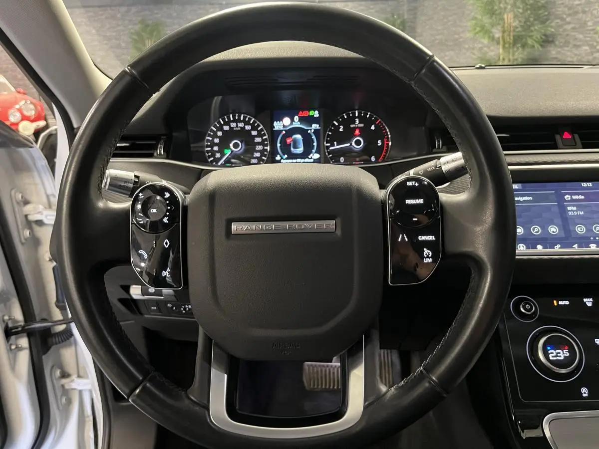 Vue rapprochée du volant cuir noir du Range Rover Evoque 2020 avec commandes intégrées et tableau de bord numérique.