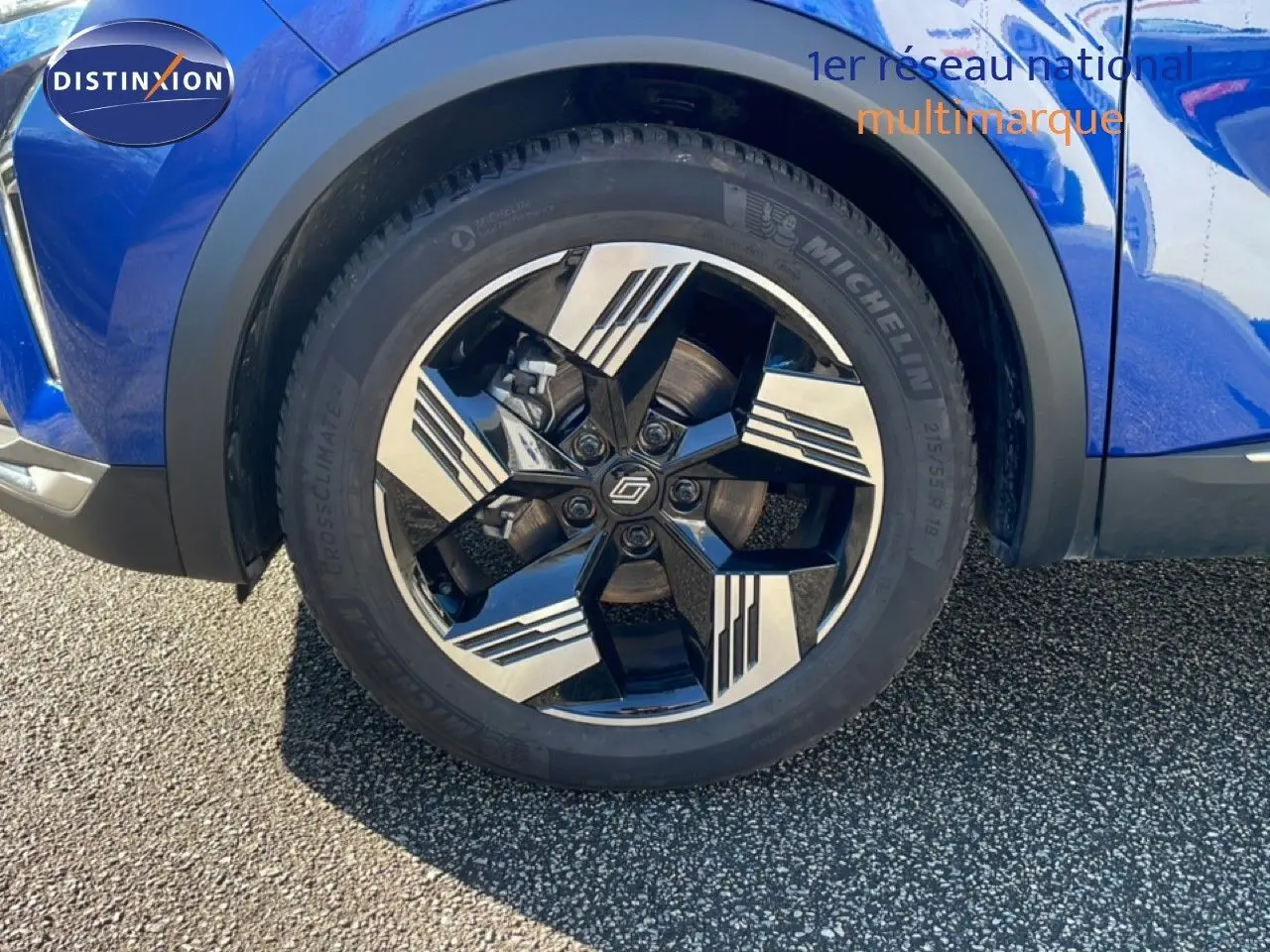 Gros plan sur la roue avant droite d'une Renault Symbioz bleu iron metal avec jante alliage noire et argentée.