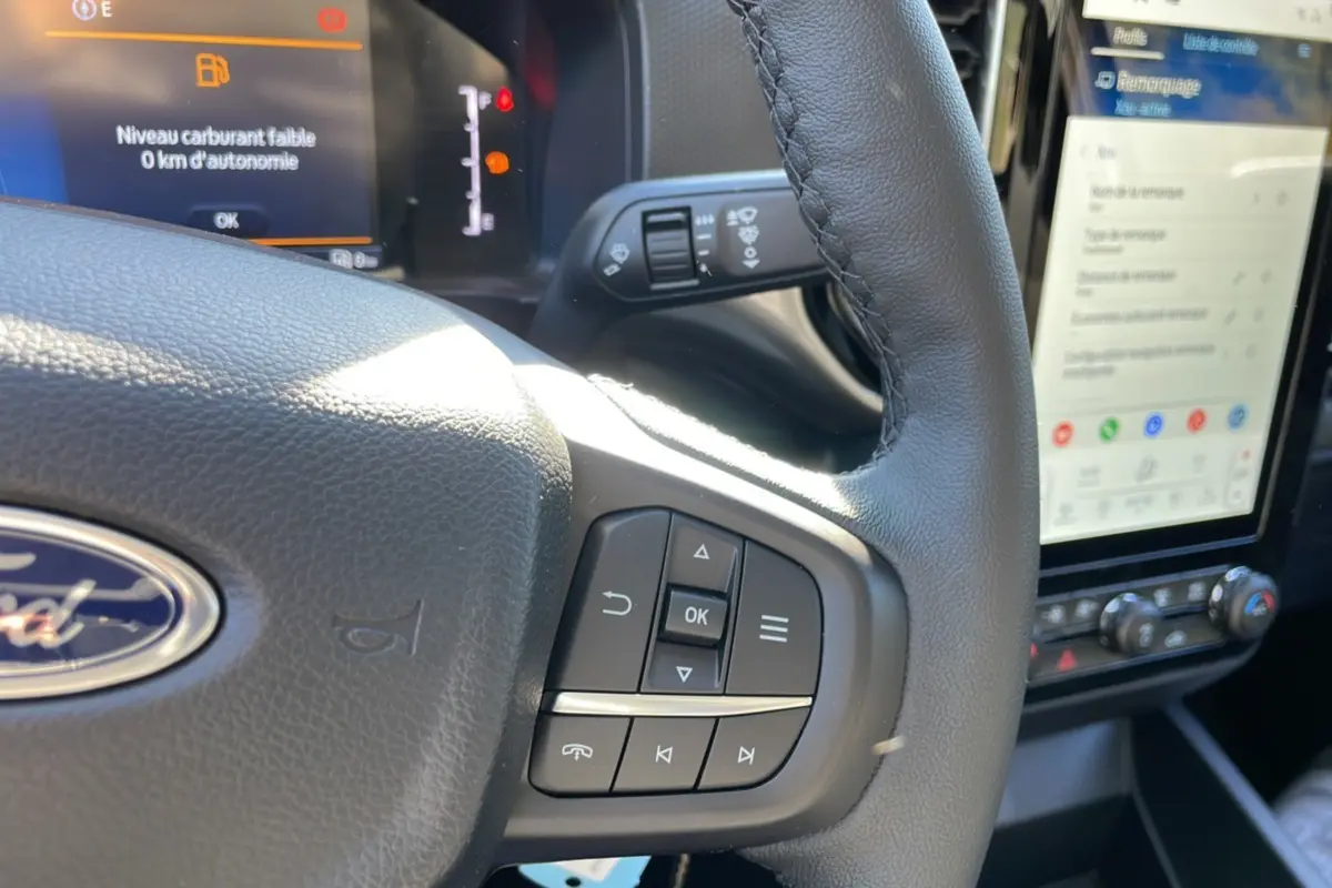 Gros plan sur le volant cuir multifonctions du Ford Ranger 2025, avec écran tactile et tableau de bord visible.