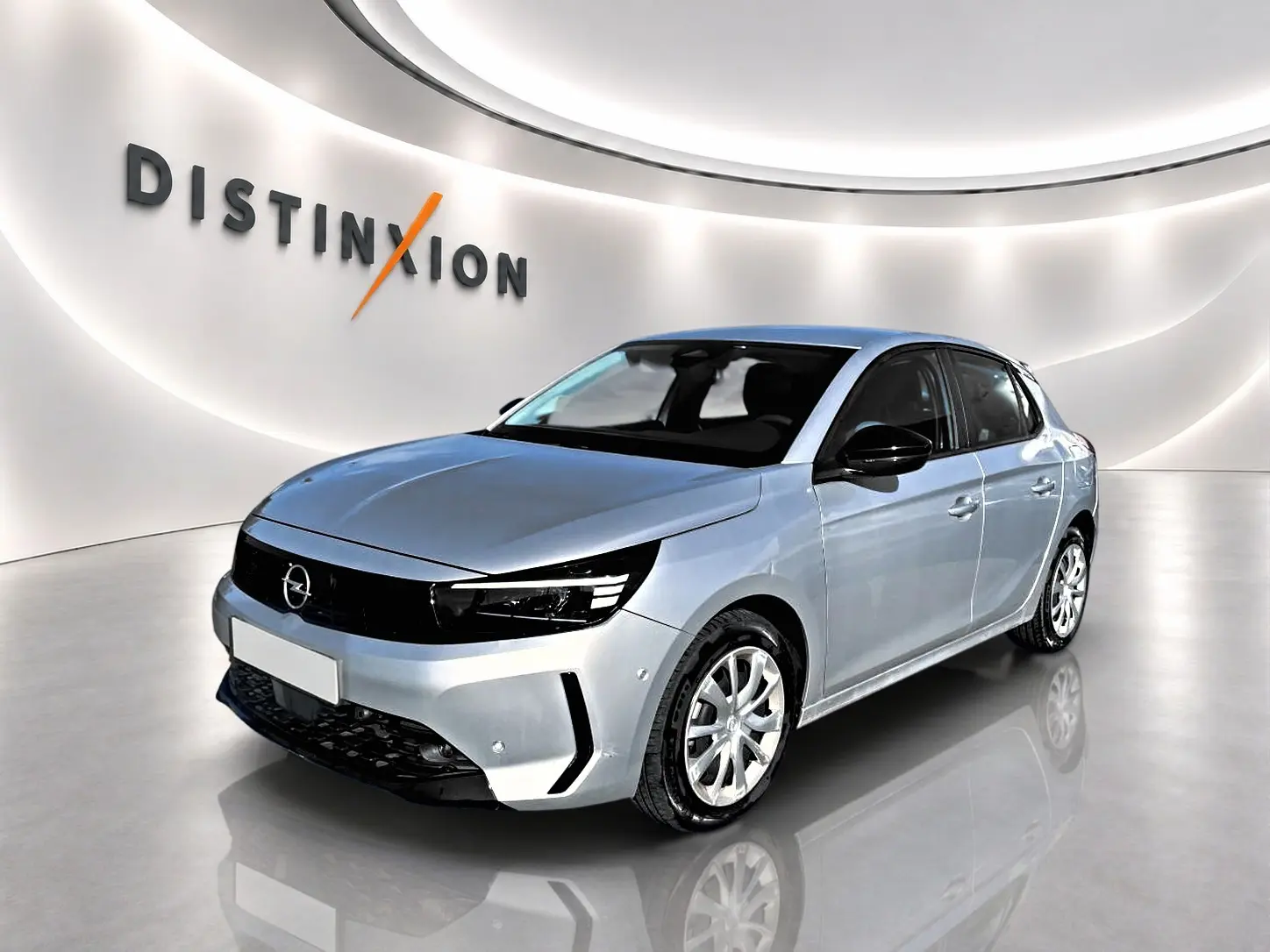Opel Corsa gris alu vue 3/4 avant droit dans un showroom lumineux avec logo Distinxion en arrière-plan.