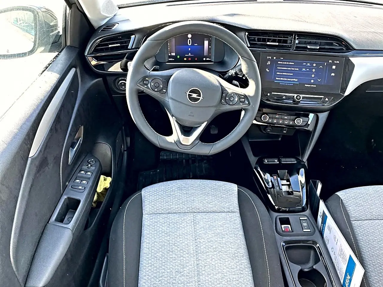 Vue intérieure avant de l'Opel Corsa 1.2 turbo 2025, volant multifonction, écran tactile et sièges tissu gris clair.