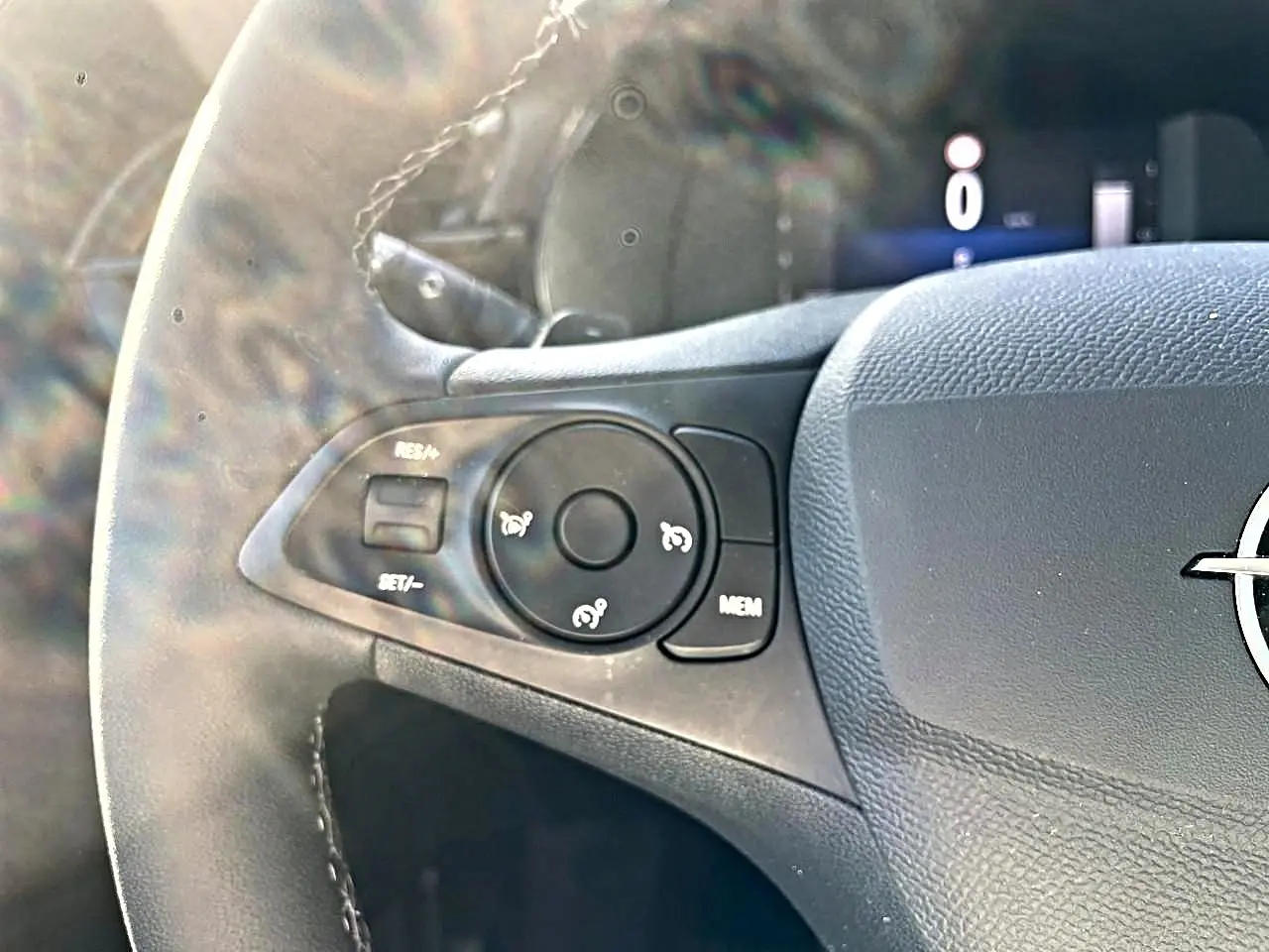 Gros plan sur la partie gauche du volant sport noir de l’Opel Corsa 2025 avec commandes multifonctions et logo Opel visible.