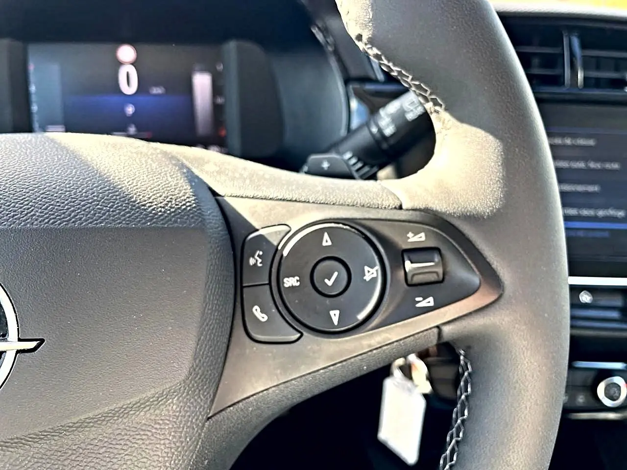Gros plan sur le volant multifonction noir de l’Opel Corsa 1.2 turbo 100 edition, avec commandes audio visibles.