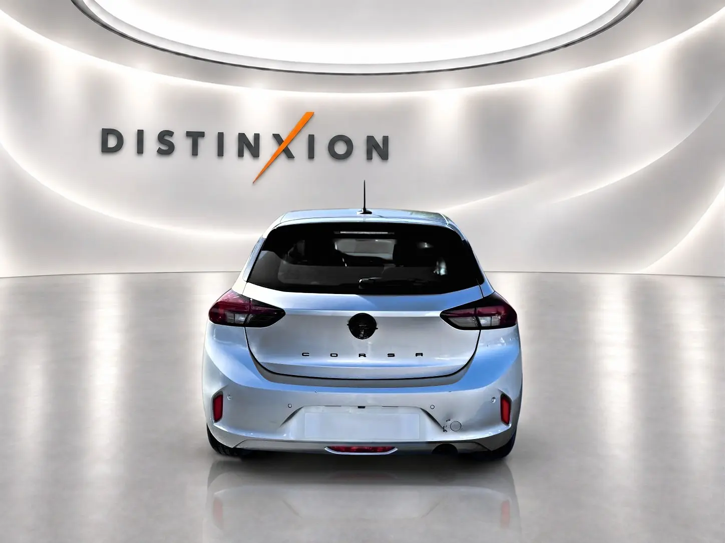 Vue arrière d'une Opel Corsa gris alu 2025 dans un showroom lumineux avec logo Distinxion en arrière-plan.