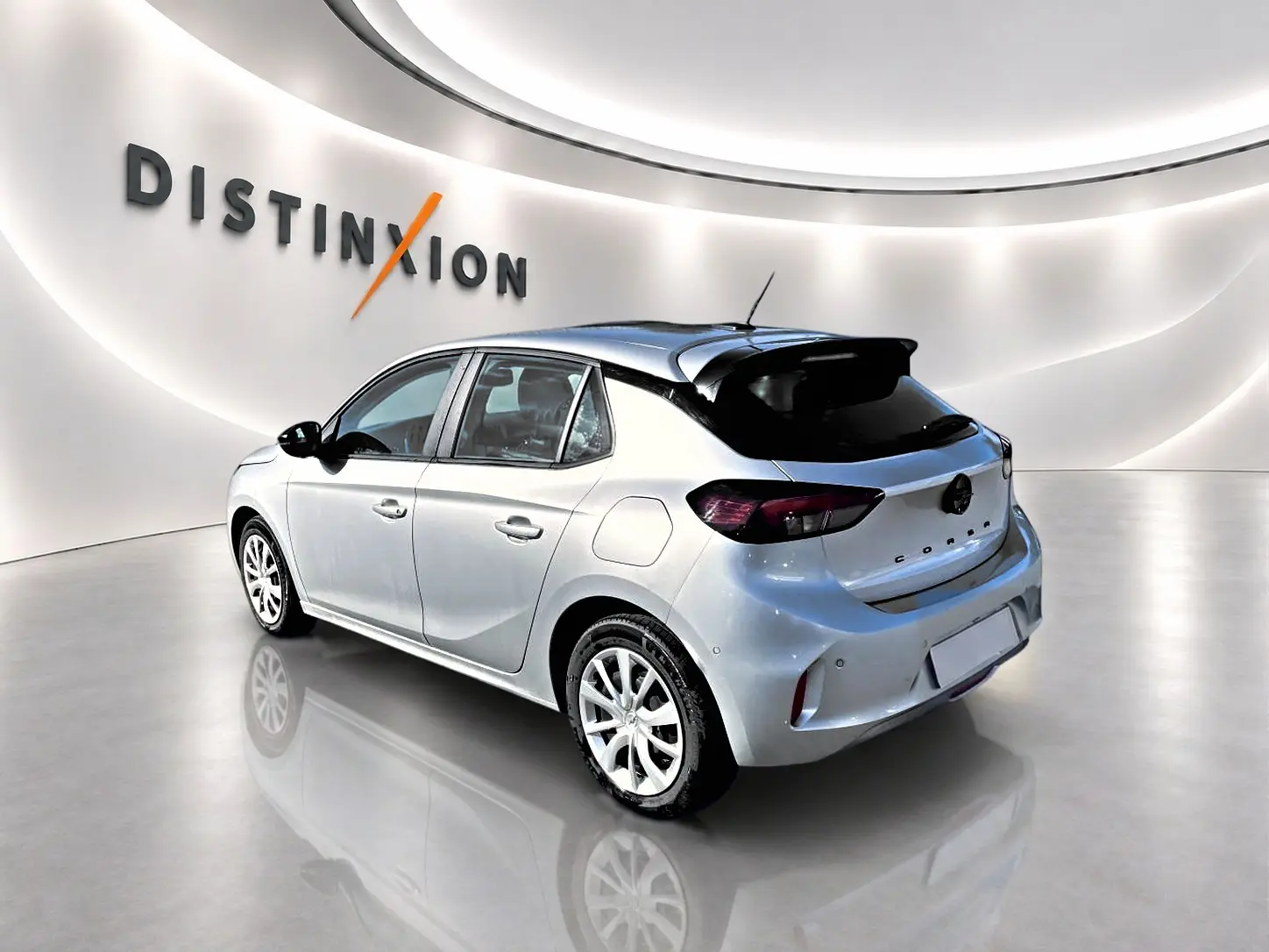 Opel Corsa gris alu vue 3/4 arrière droit en intérieur avec toit noir et becquet arrière distinctif.