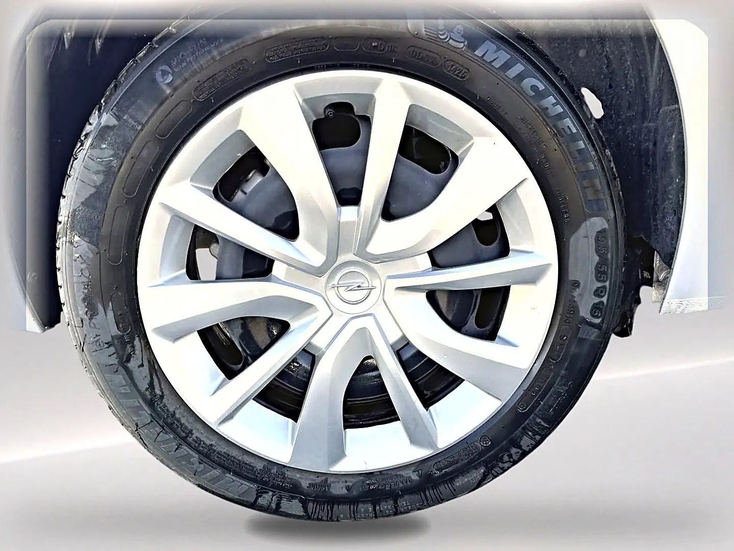 Gros plan sur la roue avant droite d’une Opel Corsa gris alu avec jante en alliage et logo Opel central.