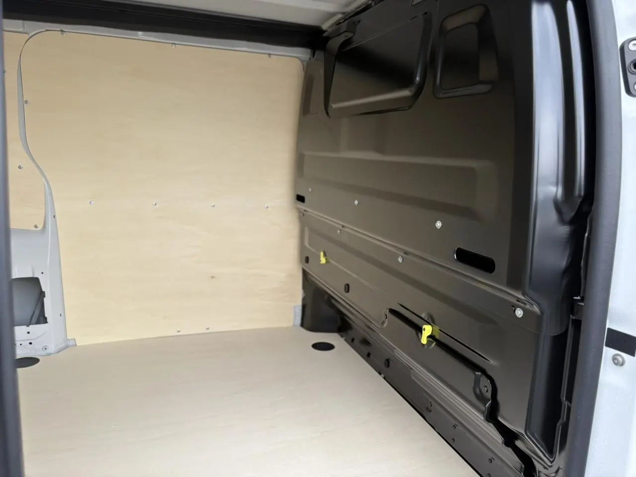 Vue intérieure de la zone de chargement du Peugeot Expert Fourgon blanc Icy, avec parois en bois clair et cloison noire.