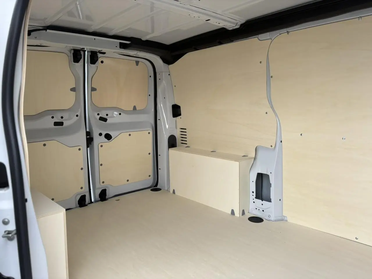 Vue intérieure arrière du Peugeot Expert Fourgon blanc Icy montrant l'espace de chargement avec habillage bois clair.