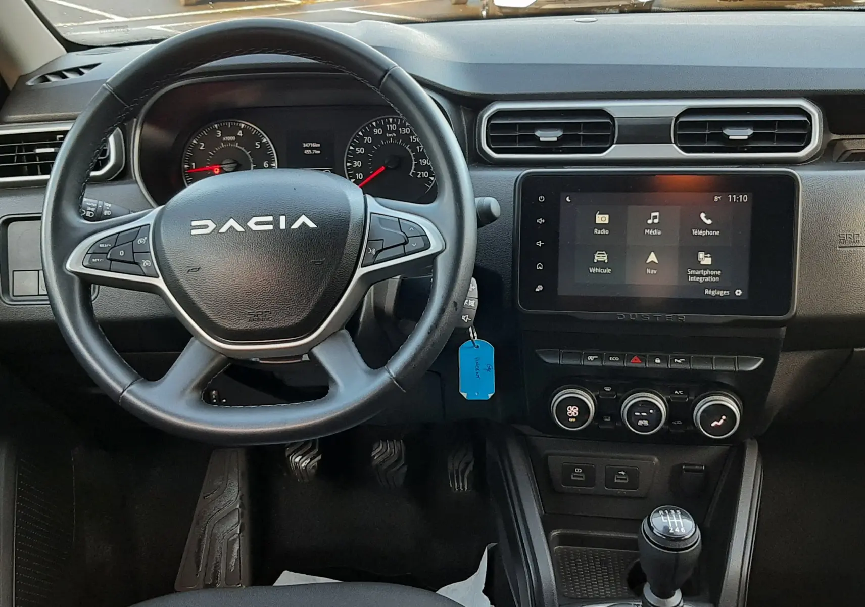 Vue intérieure centrée sur le volant et la console centrale du Dacia Duster 2023, avec boîte manuelle et écran tactile.