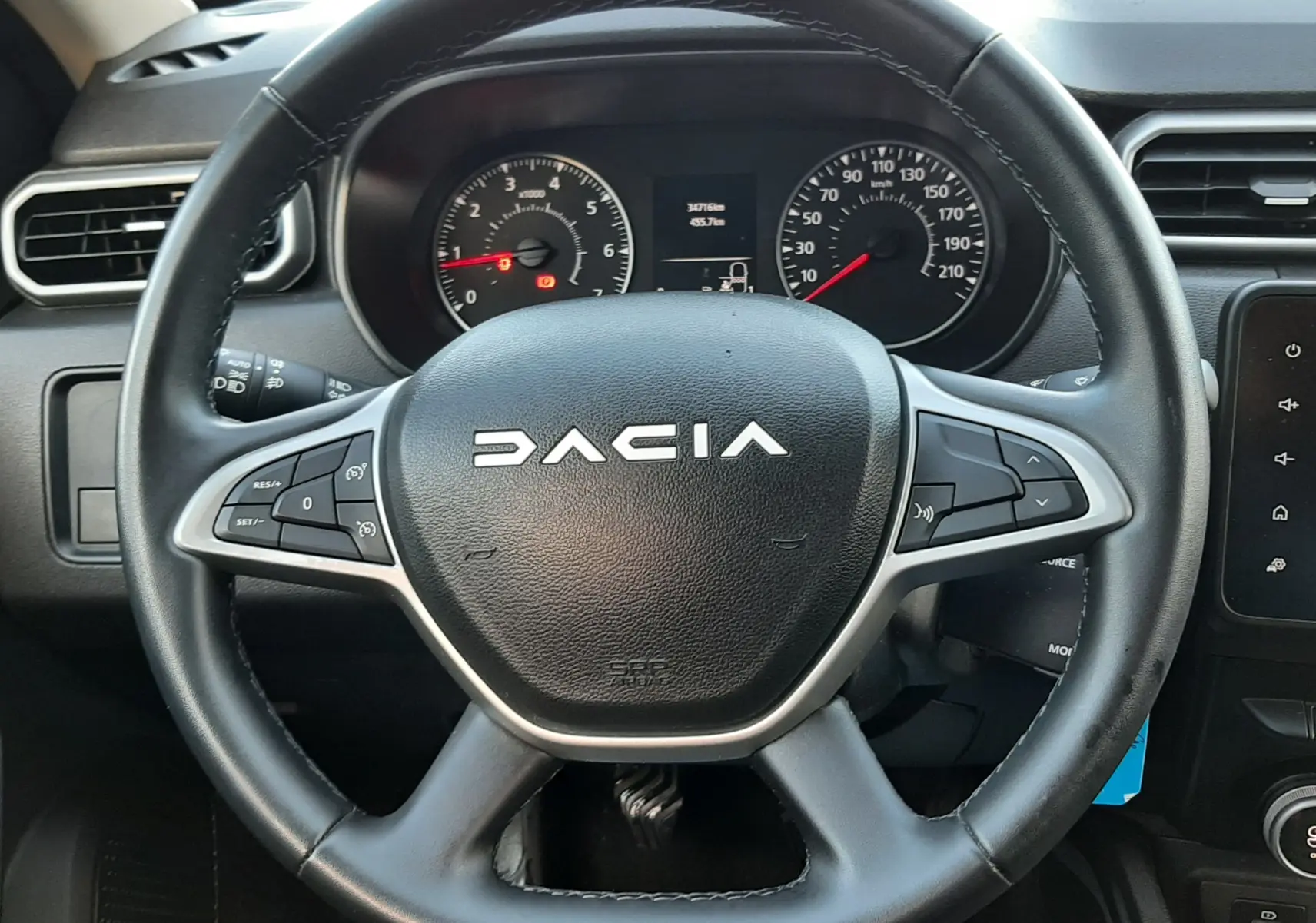 Vue rapprochée du volant noir du Dacia Duster 2023 avec tableau de bord et commandes intégrées visibles.