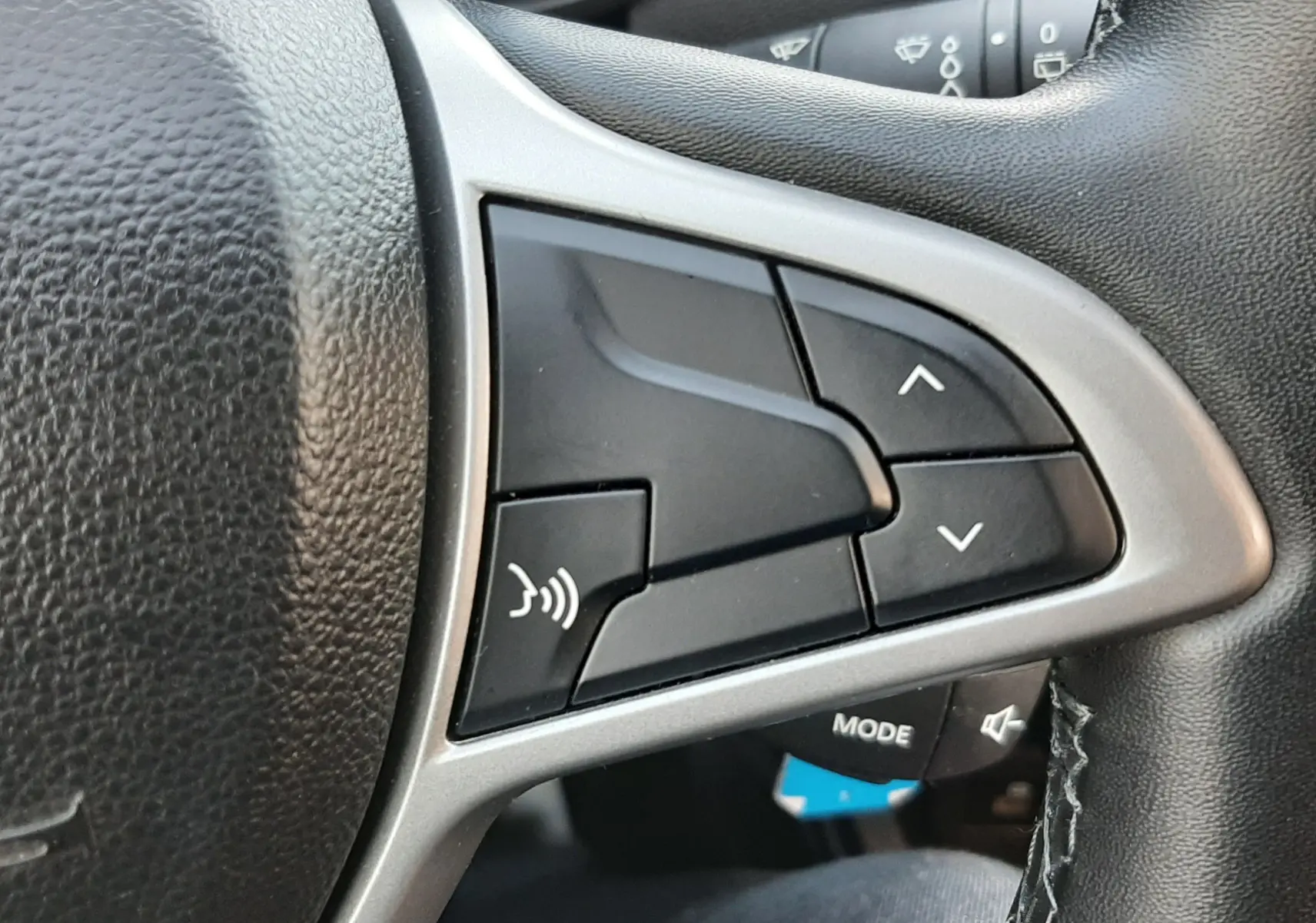 Gros plan sur les commandes au volant côté droit du Dacia Duster 2023, intérieur noir avec surpiqûres visibles.