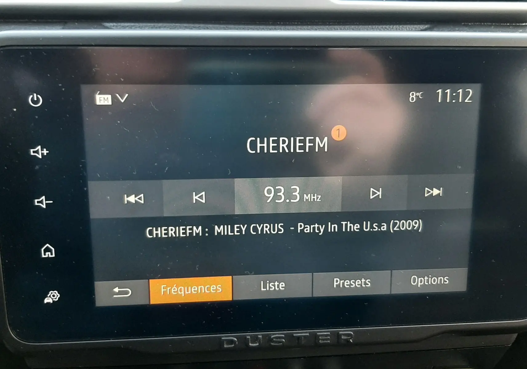Écran tactile central du Dacia Duster 2023 affichant la radio FM avec la station CHERIEFM et la chanson en cours.