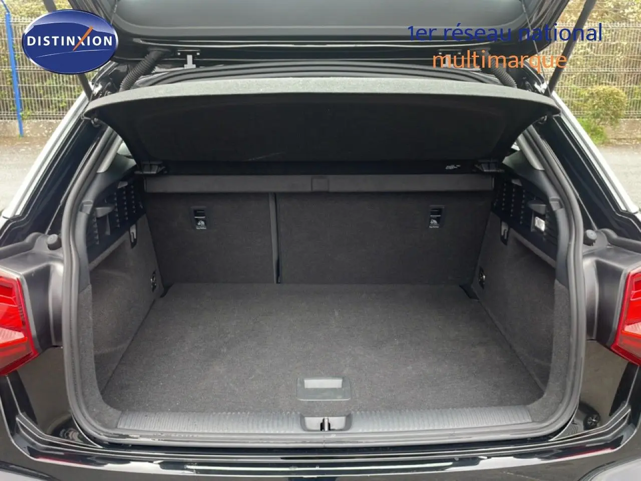 Coffre ouvert vu de l'arrière d'un Audi Q2 noir mito metal, montrant l'espace de chargement vide et propre.
