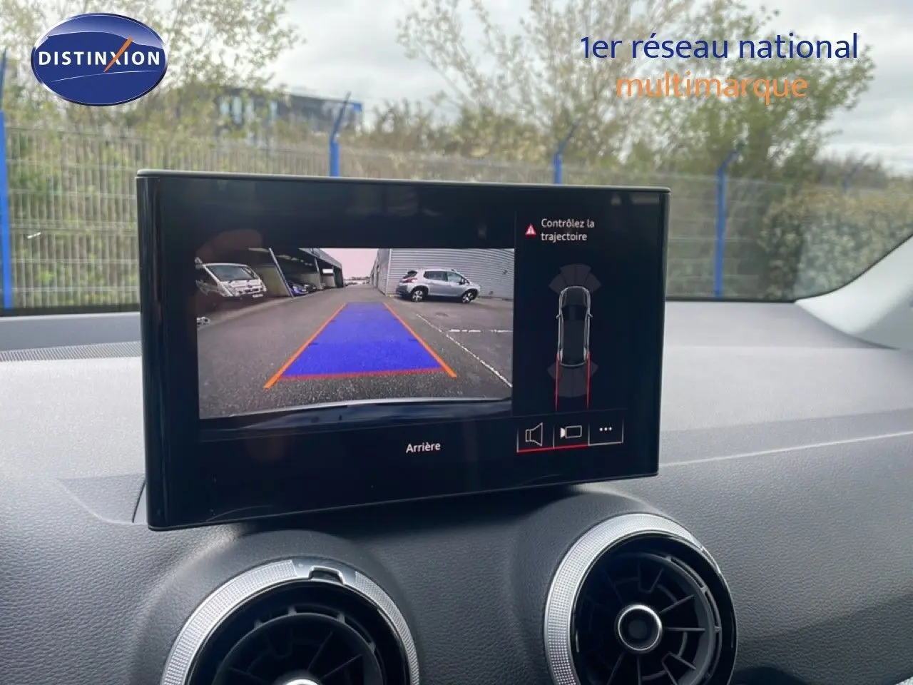 Écran central affichant la caméra de recul avec guidage en bleu dans l’Audi Q2 noir mito metal, vue intérieure avant.