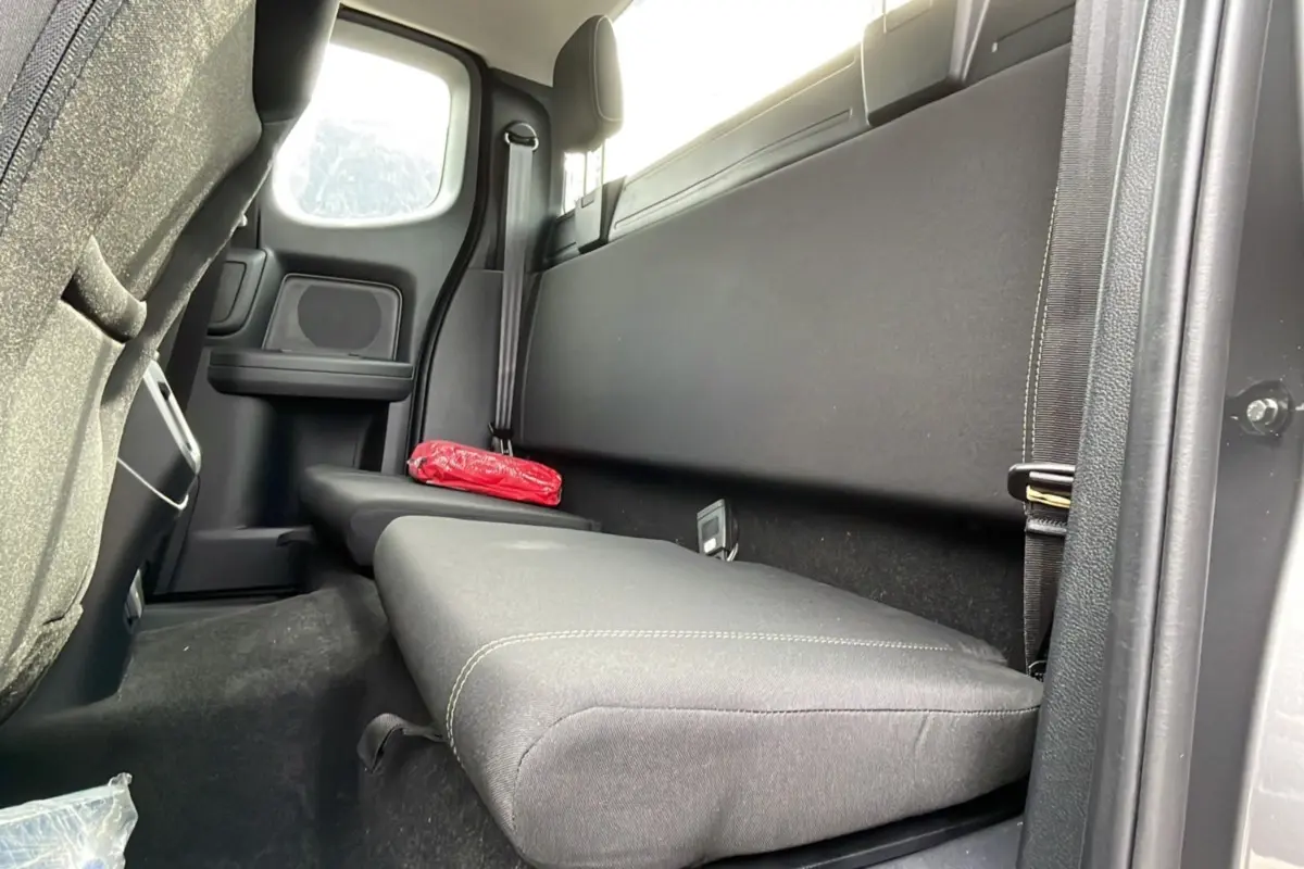 Vue intérieure arrière côté droit du Ford Ranger gris carbone, banquette simple avec ceinture de sécurité et trousse de secours rouge.