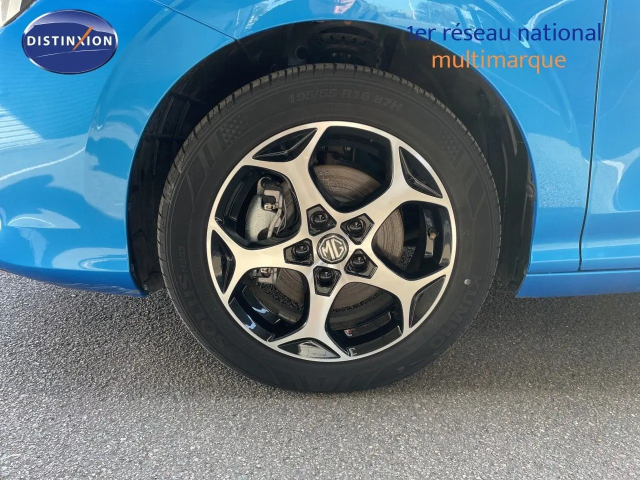 Gros plan sur la roue avant droite d'une MG3 2024 bleu Como Metal avec jante alliage bicolore et logo MG au centre.