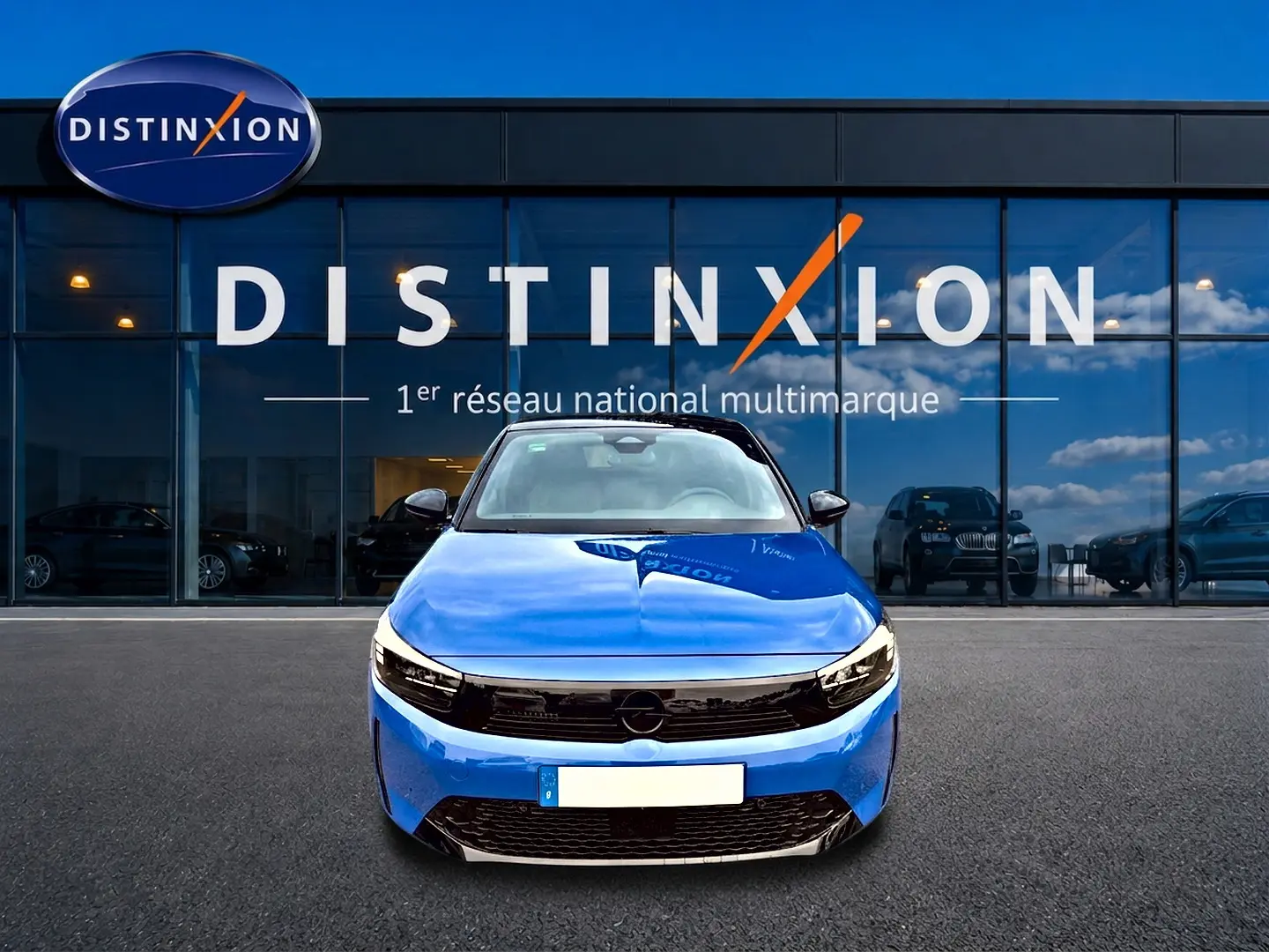 Opel Corsa 1.2 turbo bleu vue de face, avec calandre noire et phares LED devant un showroom Distinxion.