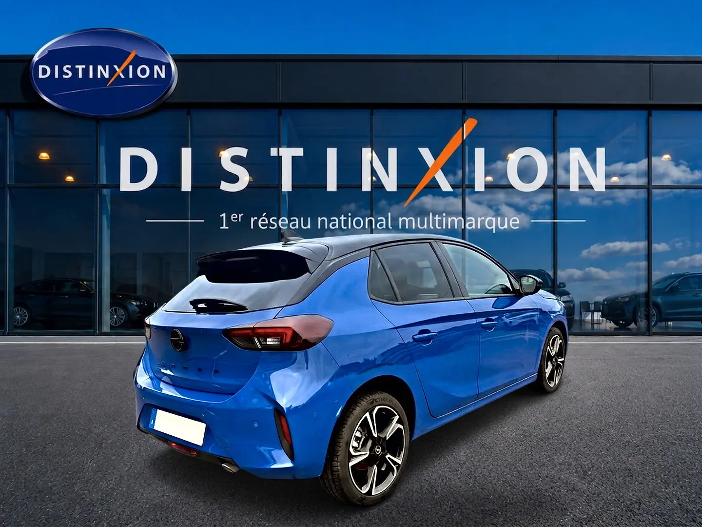 Opel Corsa 1.2 turbo bleu en 3/4 arrière droit, avec jantes alu et toit noir devant une vitrine Distinxion.