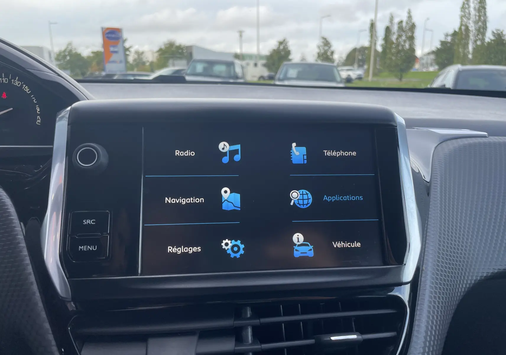 Écran tactile central du tableau de bord d'un Peugeot 2008 gris, affichant les menus radio, navigation, téléphone et véhicule.
