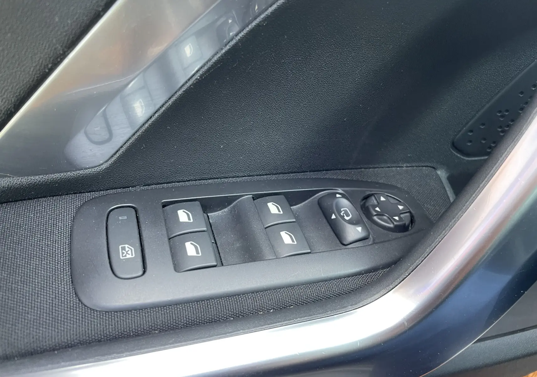 Gros plan sur les commandes de lève-vitres et réglage des rétroviseurs côté conducteur d'un Peugeot 2008 gris 2019.