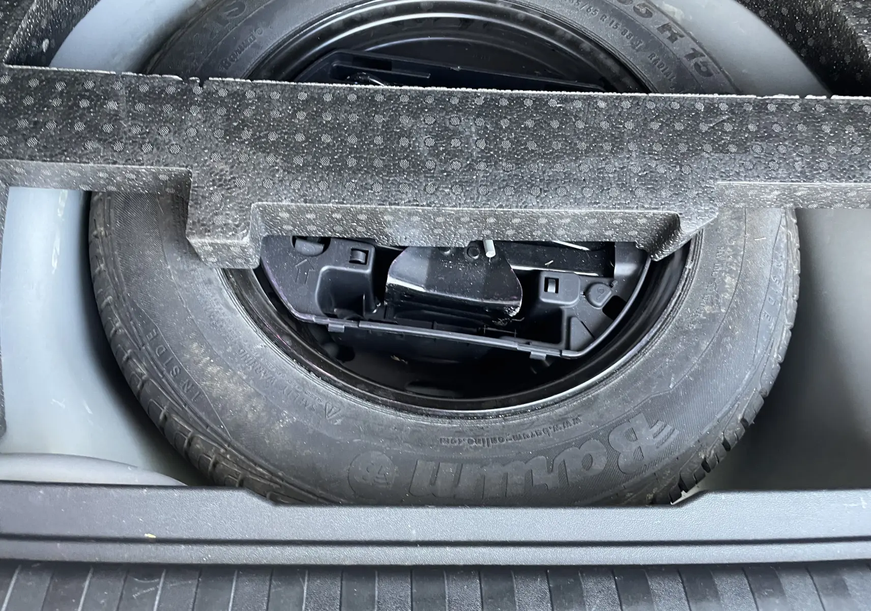 Gros plan sur la roue de secours noire logée dans le coffre d'un Peugeot 2008 gris 2019.