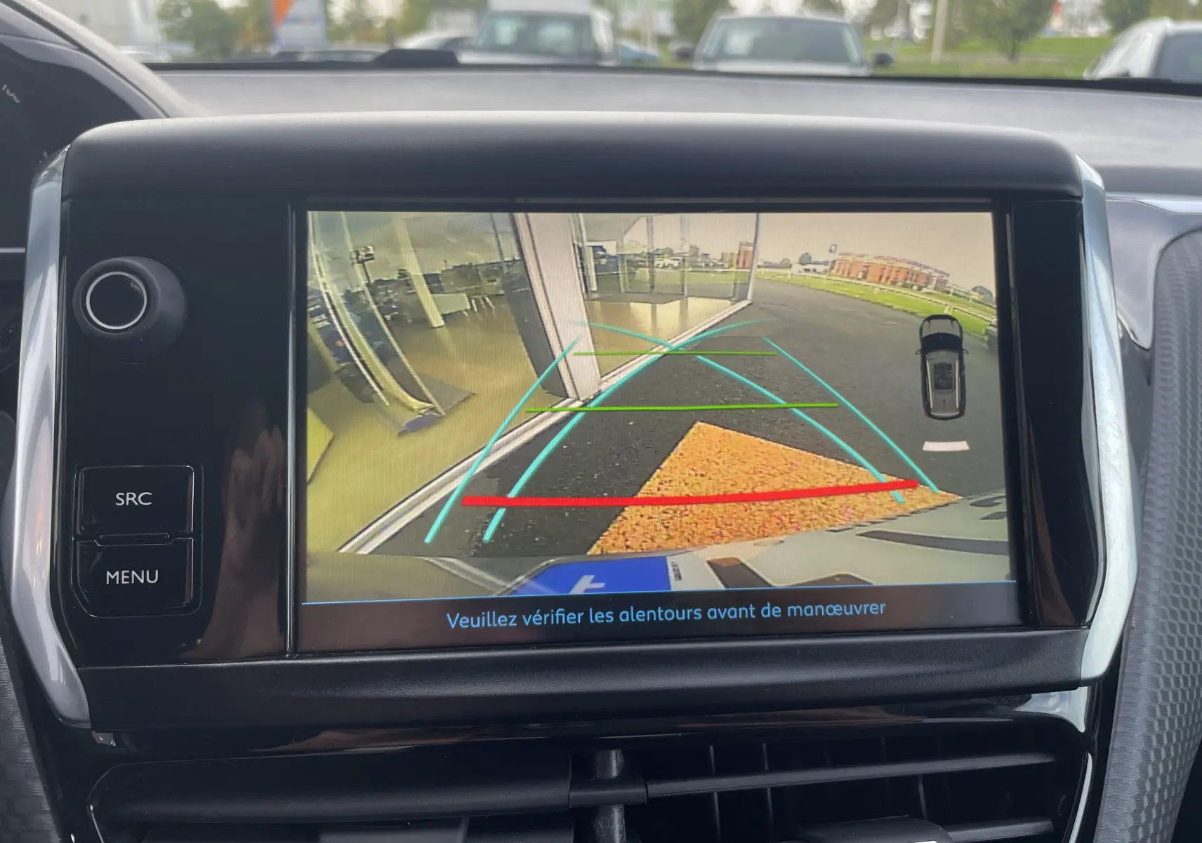 Écran de caméra de recul du Peugeot 2008 gris, montrant les lignes d'aide au stationnement et l'arrière du véhicule.