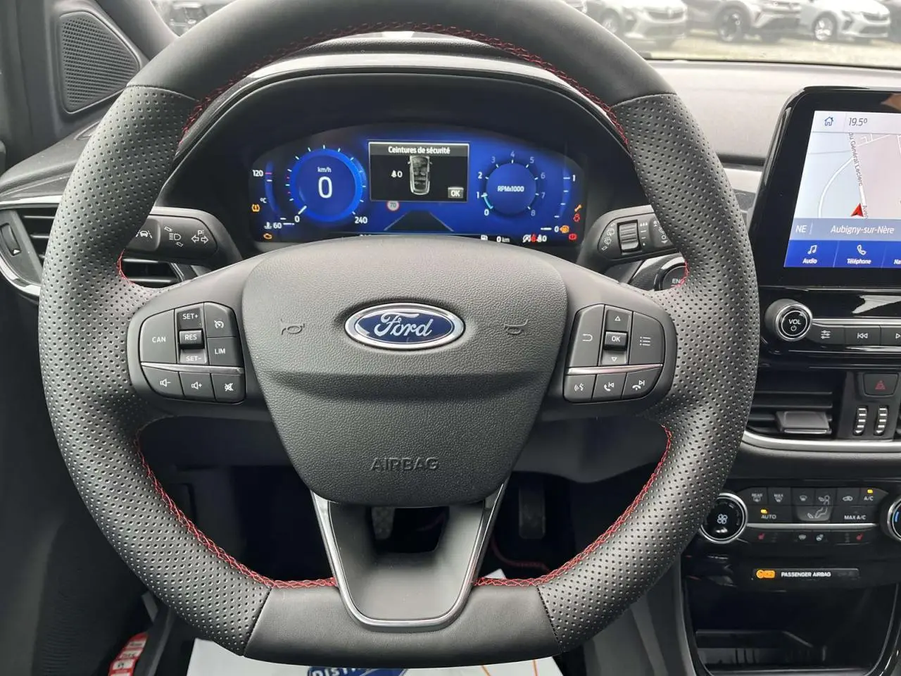 Vue rapprochée du volant perforé avec surpiqûres rouges et tableau de bord numérique du Ford Puma 2023.