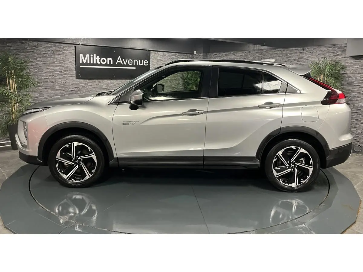 Vue de profil côté gauche d'un Mitsubishi Eclipse Cross gris métallisé avec jantes alliage bi-ton et toit noir.