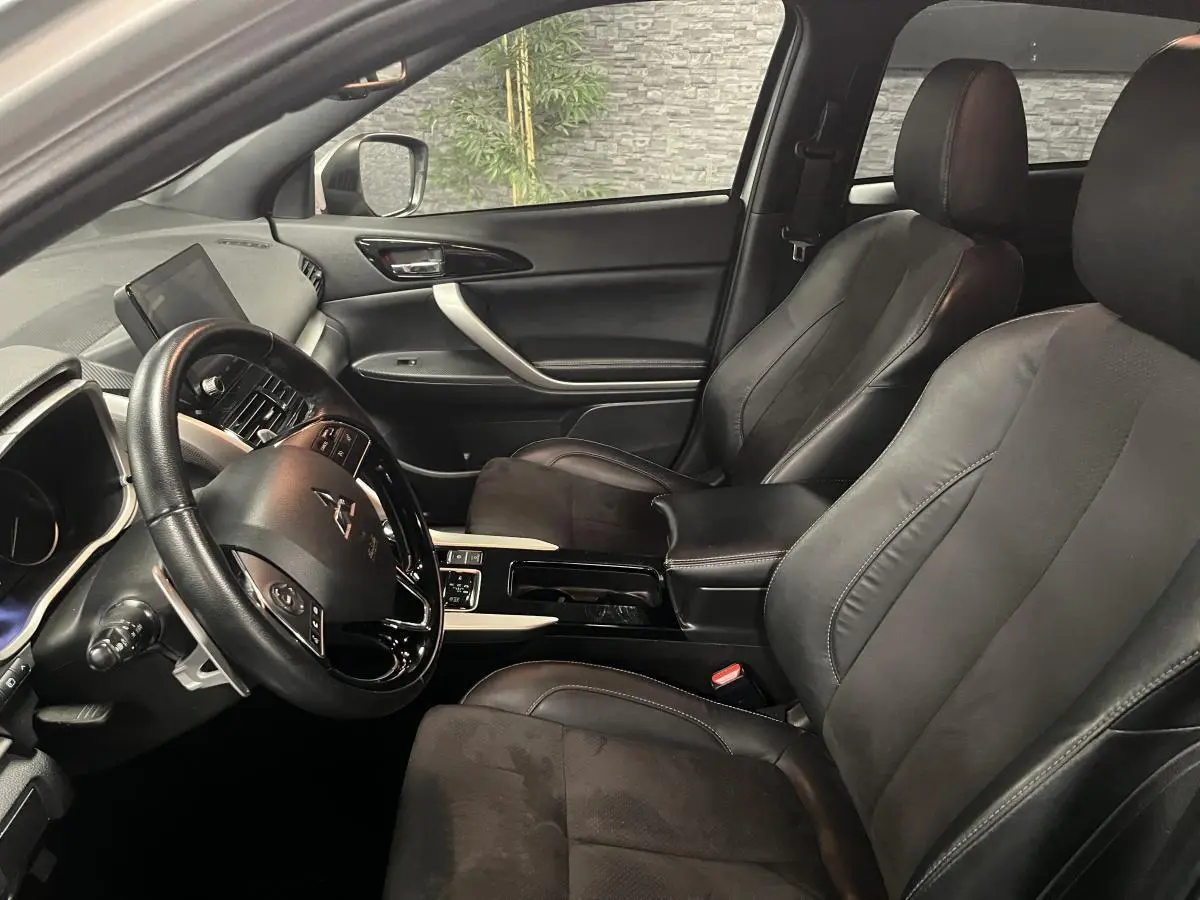 Intérieur avant du Mitsubishi Eclipse Cross 2022, sièges en cuir noir et tableau de bord avec écran tactile visible côté gauche.