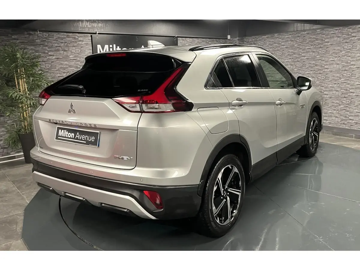 Vue 3/4 arrière droite du Mitsubishi Eclipse Cross gris métallisé avec toit noir et jantes alliage bi-ton dans un showroom.