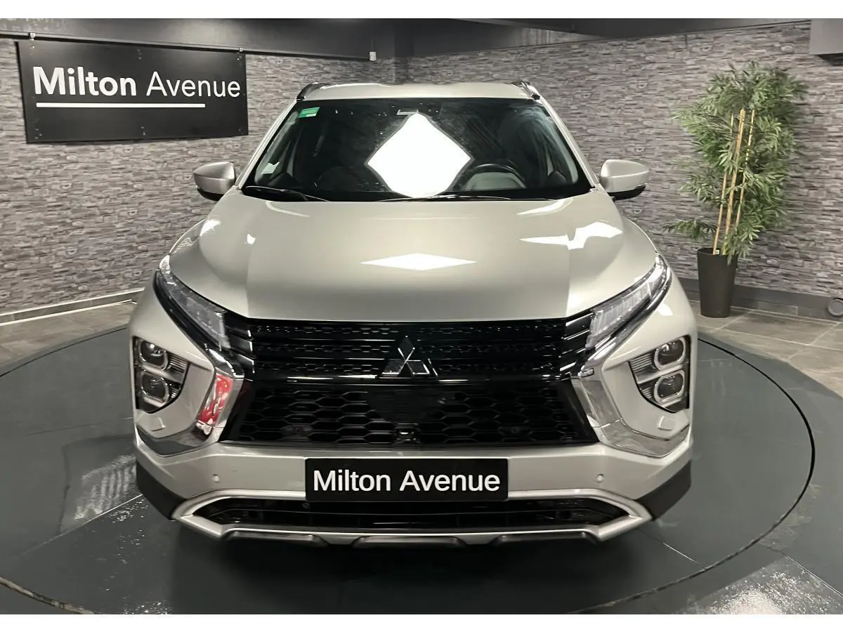 Vue frontale du Mitsubishi Eclipse Cross gris métallisé avec calandre noire et éclairage LED distinctif en intérieur showroom.