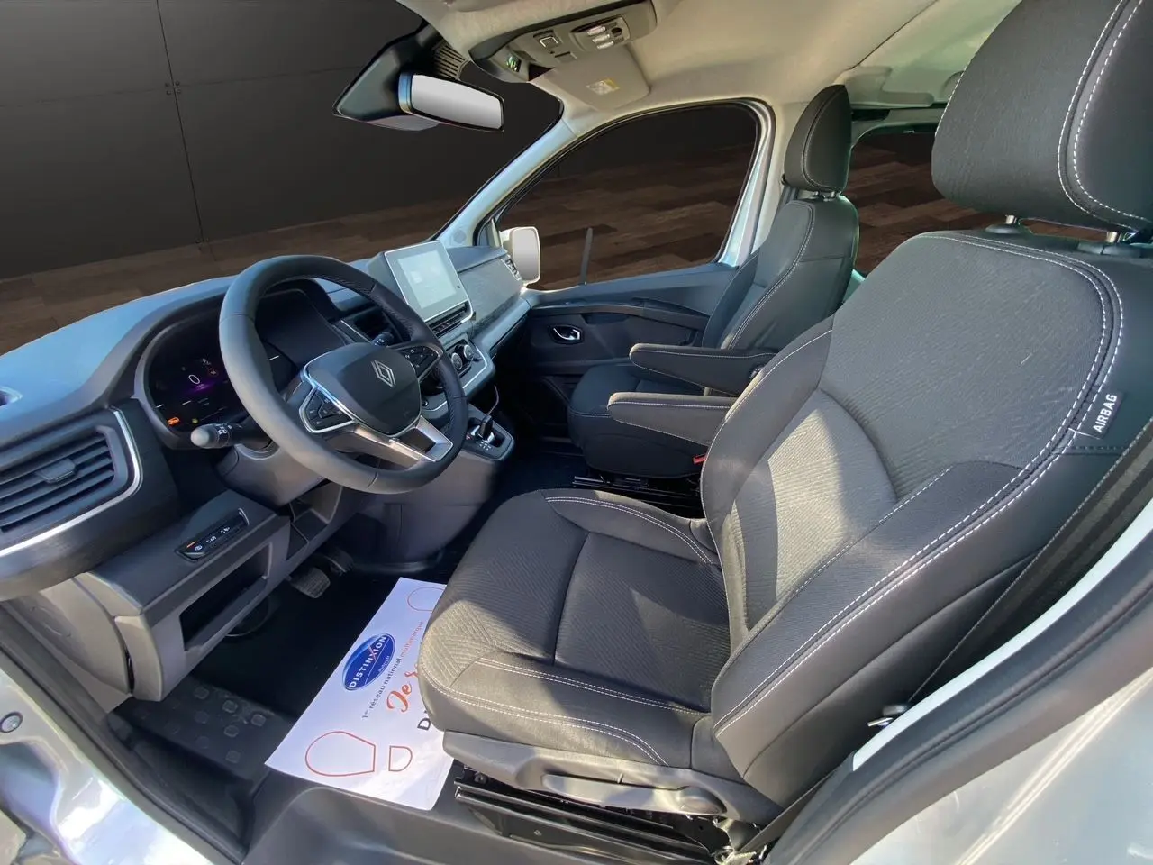 Vue intérieure avant droit du Renault Trafic Combi 2025 avec sièges tissu noir et tableau de bord digital.