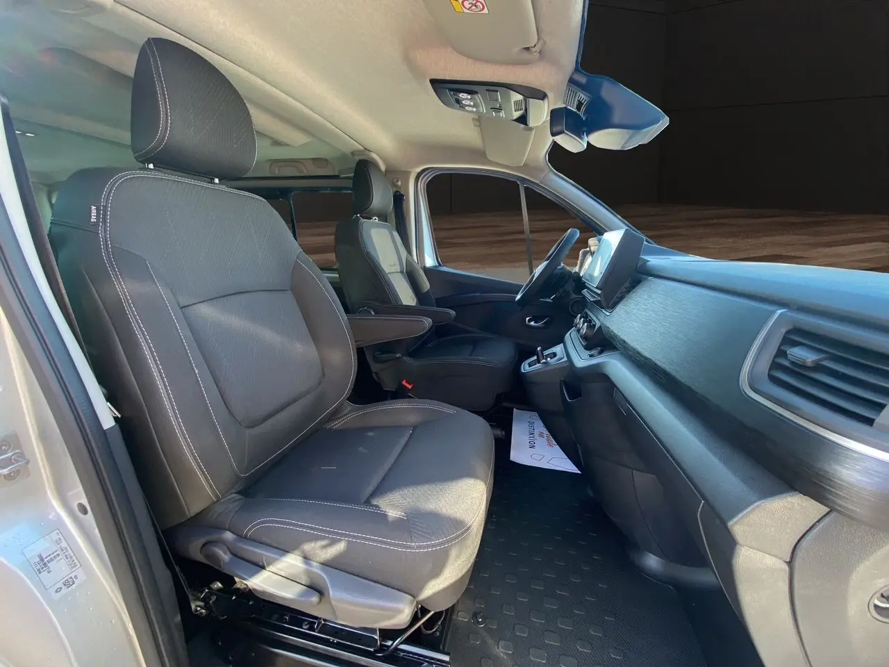 Intérieur avant du Renault Trafic Combi gris Highland 2025, sièges tissu noir avec accoudoirs et tableau de bord moderne