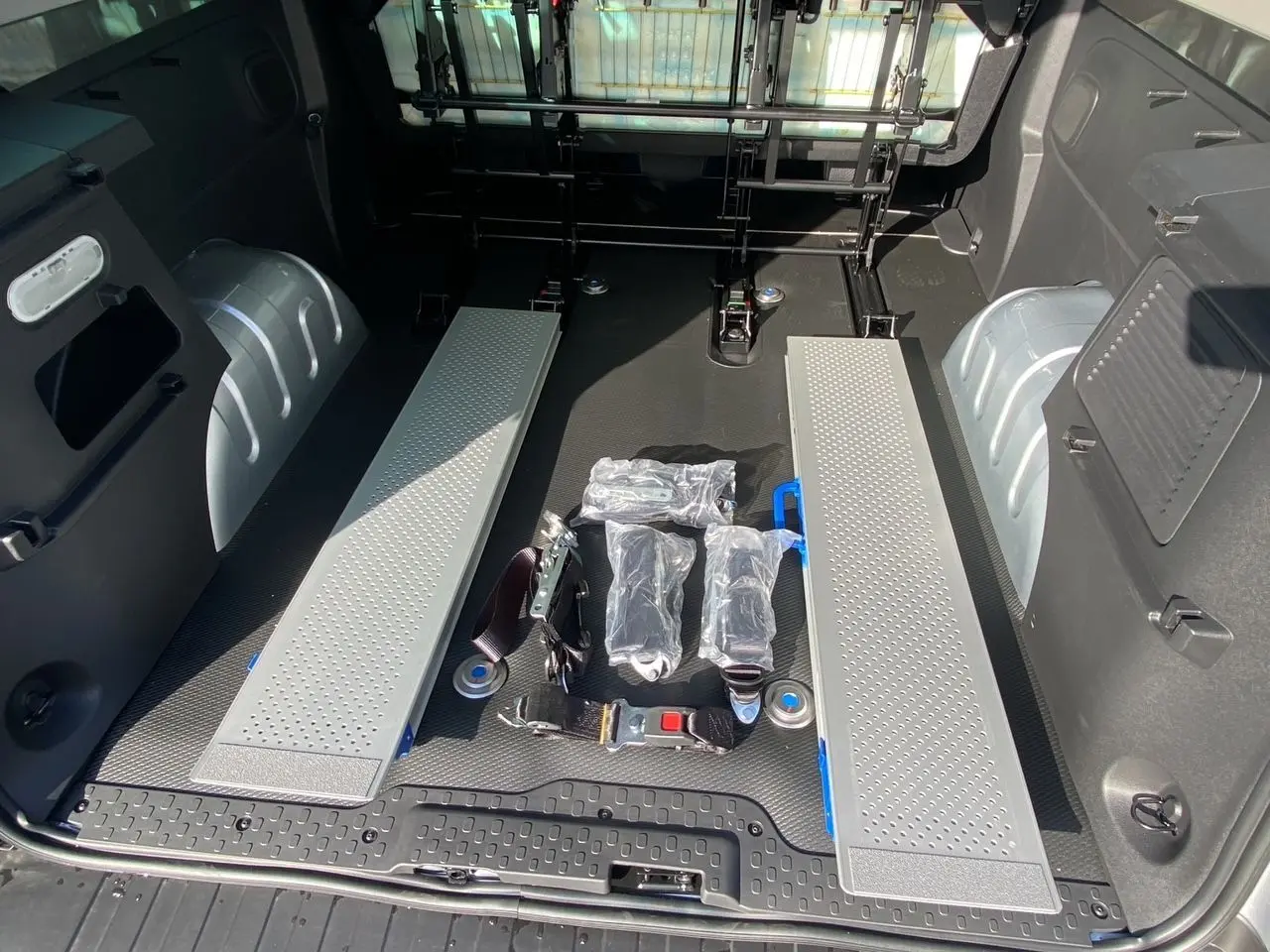 Vue intérieure arrière du coffre gris Highland du Renault Trafic Combi avec rampes et sangles de fixation au sol.