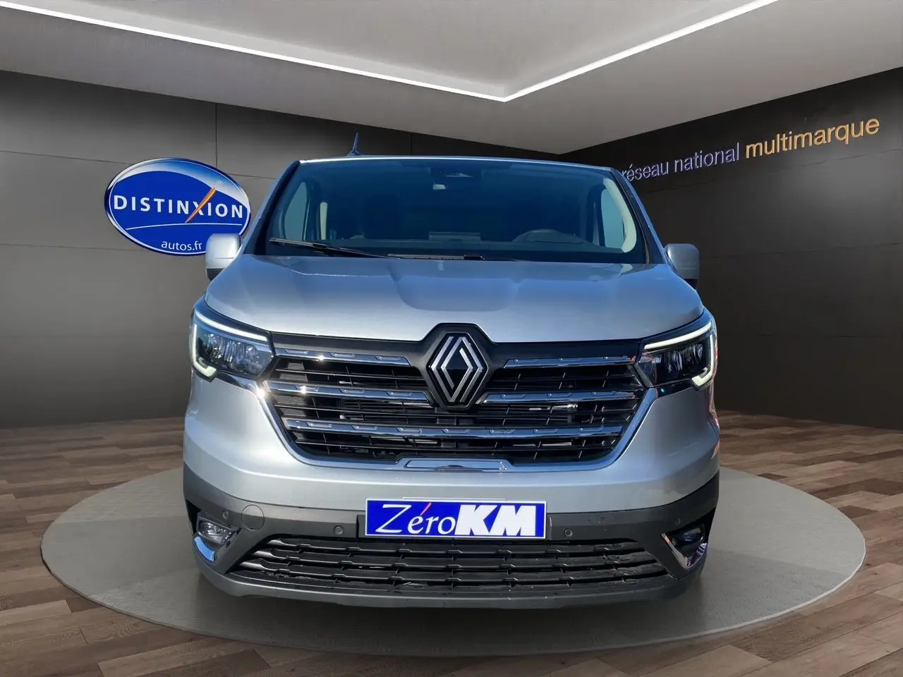 Vue de face d'un Renault Trafic Combi gris Highland avec calandre noire et feux LED allumés en showroom