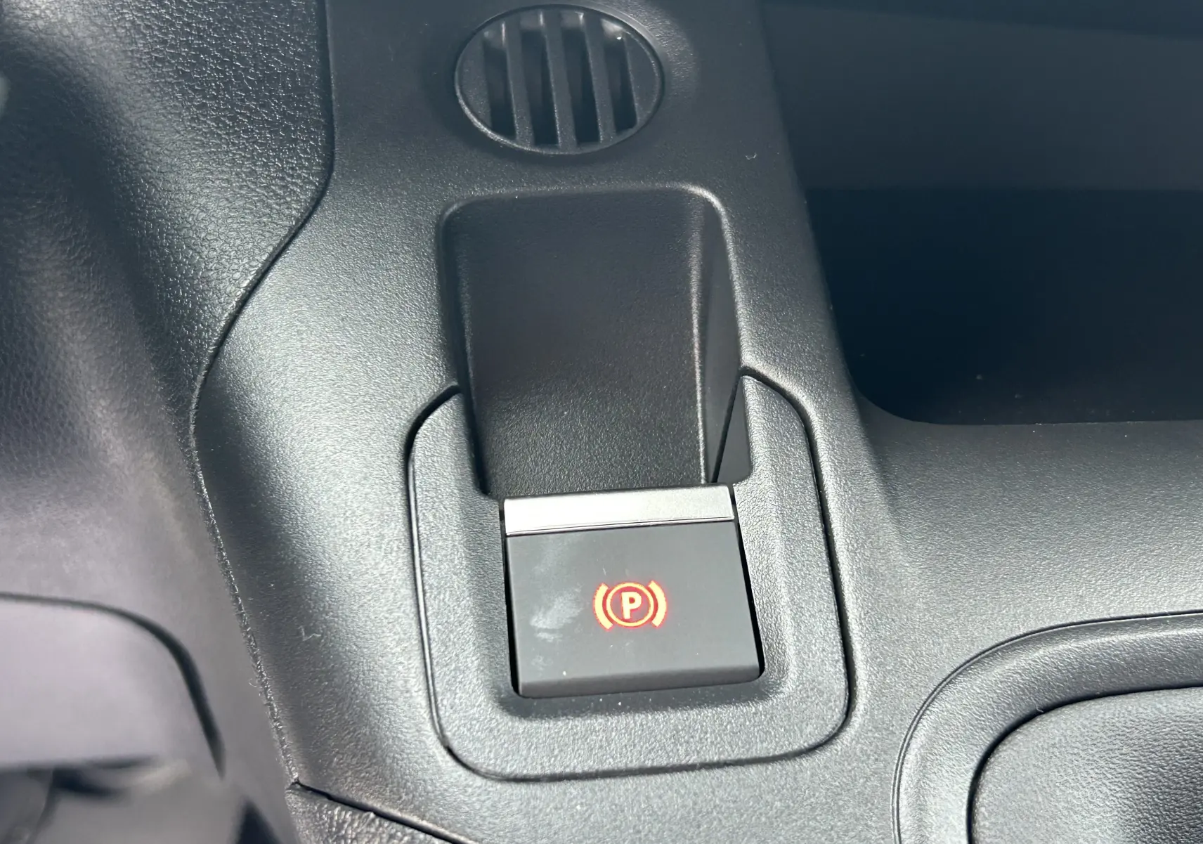 Gros plan sur le bouton de frein à main électronique rouge dans l'habitacle noir du Citroën Berlingo Fourgon 2025.