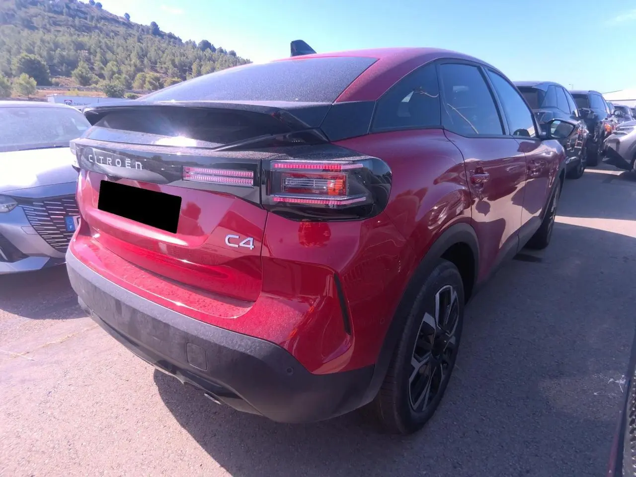 Vue 3/4 arrière droite d'une Citroën C4 hybride rouge Elixir avec toit noir et feux arrière LED distinctifs.