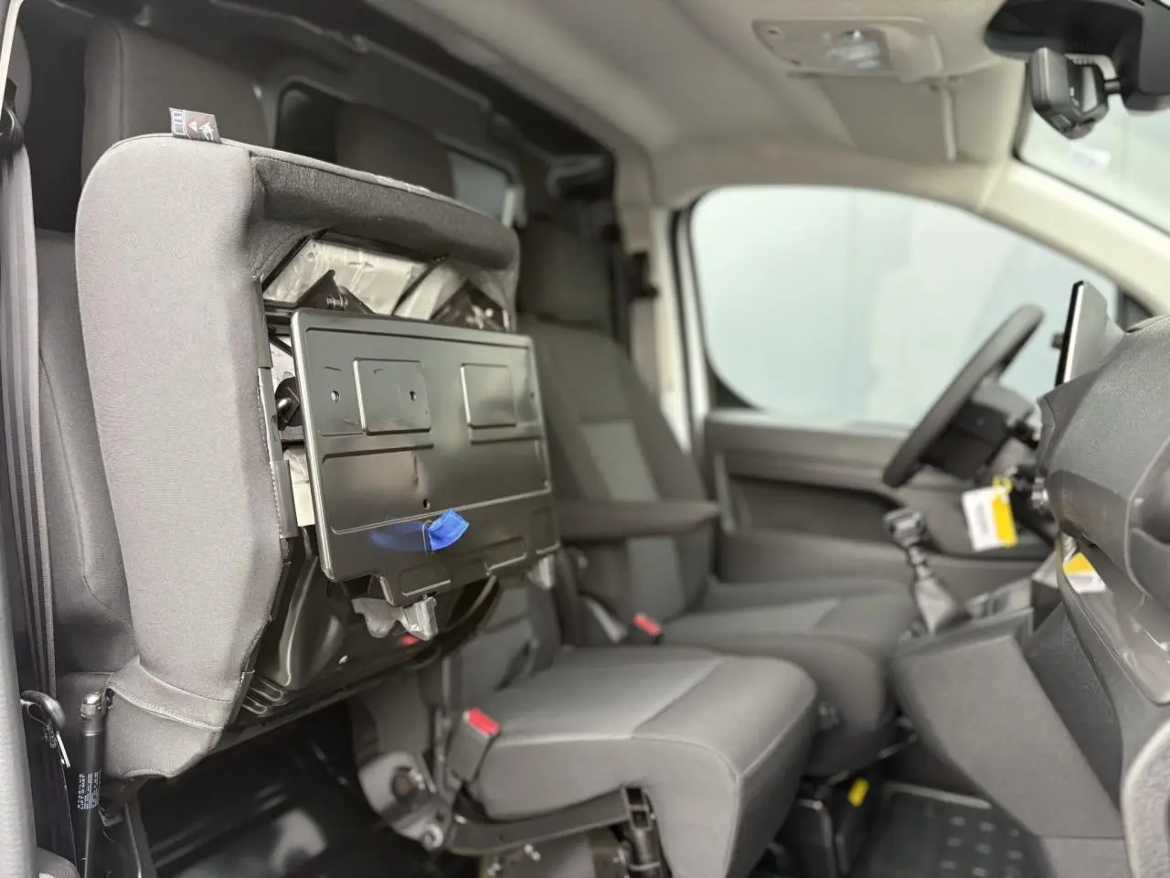 Vue intérieure côté droit du Peugeot Expert Fourgon 2025, banquette passager rabattue avec tablette écritoire visible.