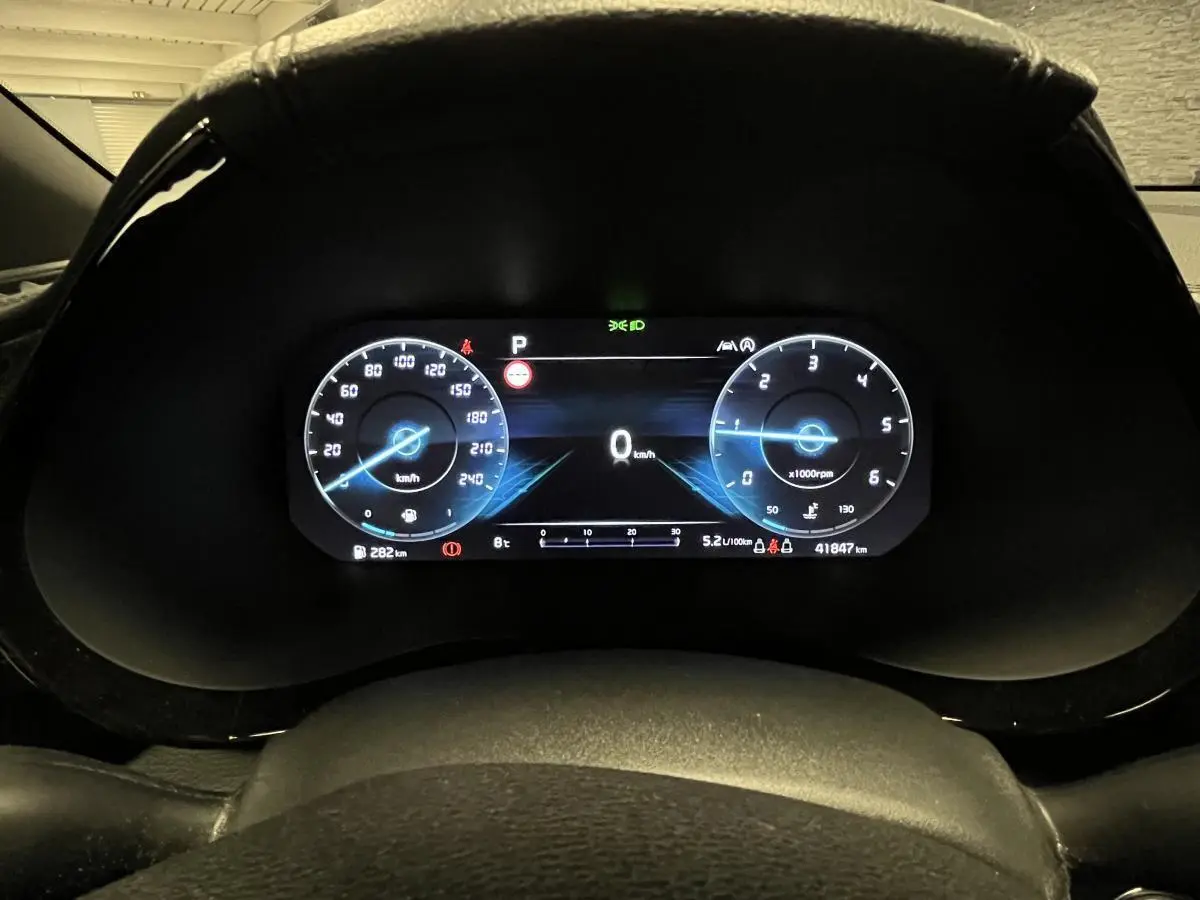 Combiné d'instrumentation digital bleu affichant la vitesse et le régime dans une Kia Ceed 2023 gris, vue depuis le volant.