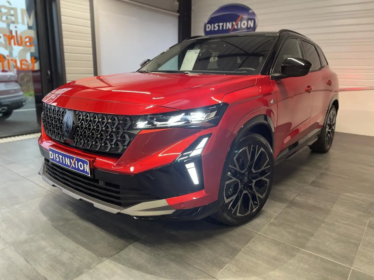 Renault Austral rouge métallisé avec toit noir, vue 3/4 avant droit, calandre noire et jantes alliage noires.