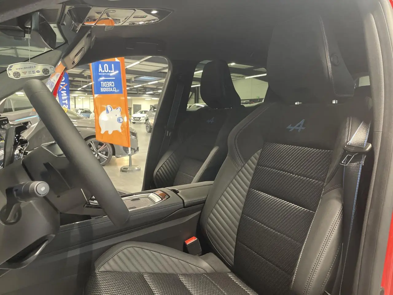 Vue intérieure côté conducteur du Renault Austral 2025, sièges en tissu carbone Alcantara noir avec surpiqûres tricolores et logo Alpine.