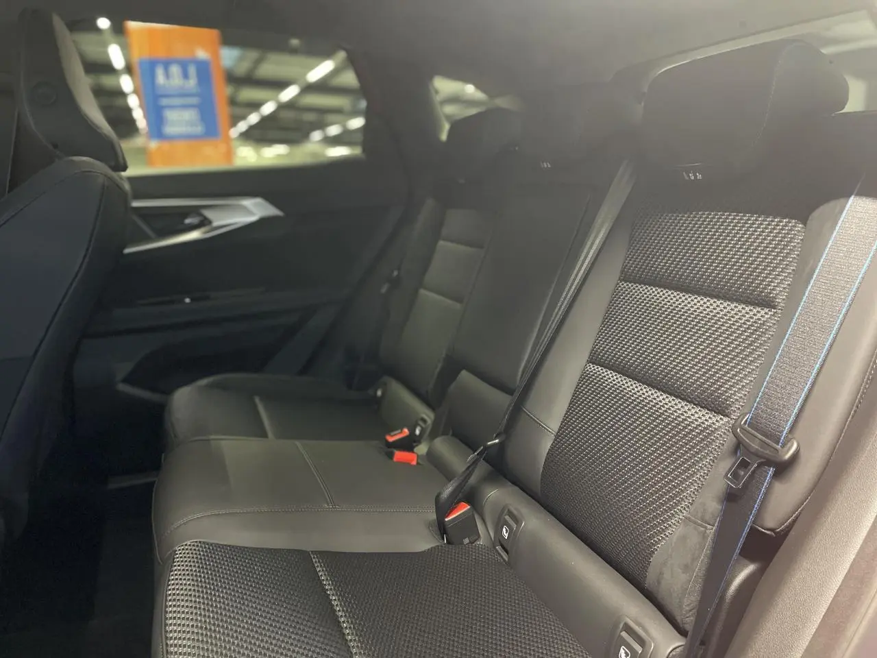 Vue latérale droite de la banquette arrière noire en tissu carbone et Alcantara avec surpiqûres tricolores dans un Renault Austral 2025.