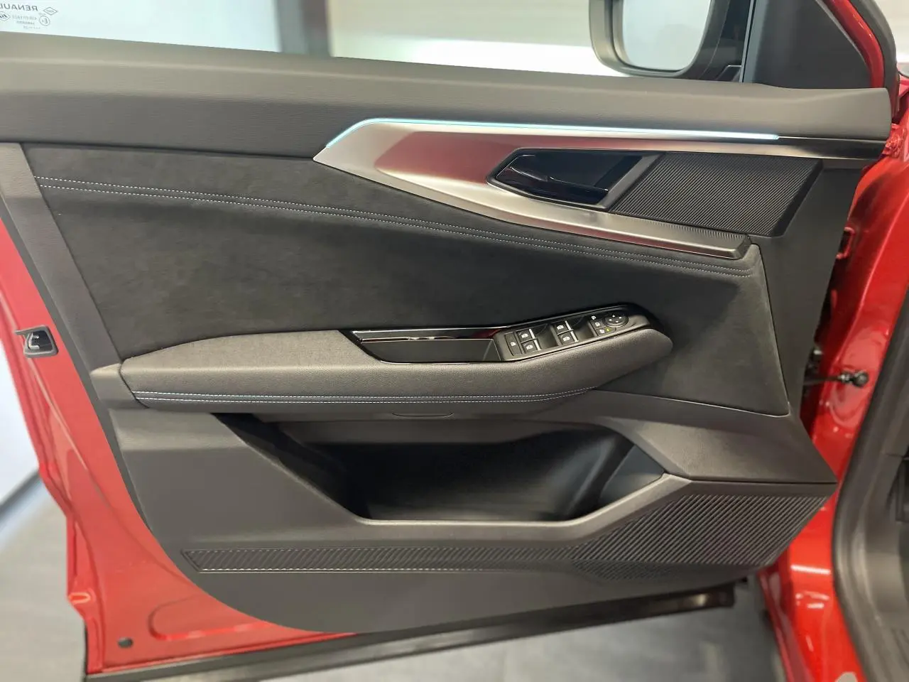 Porte avant gauche rouge métallisé de Renault Austral 2025 avec garniture Alcantara noire et commandes de vitres.