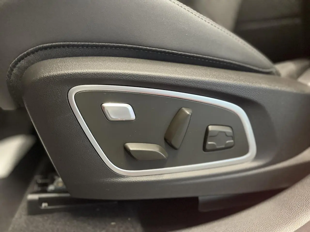 Gros plan sur les commandes électriques de réglage du siège conducteur du Renault Austral rouge métallisé.