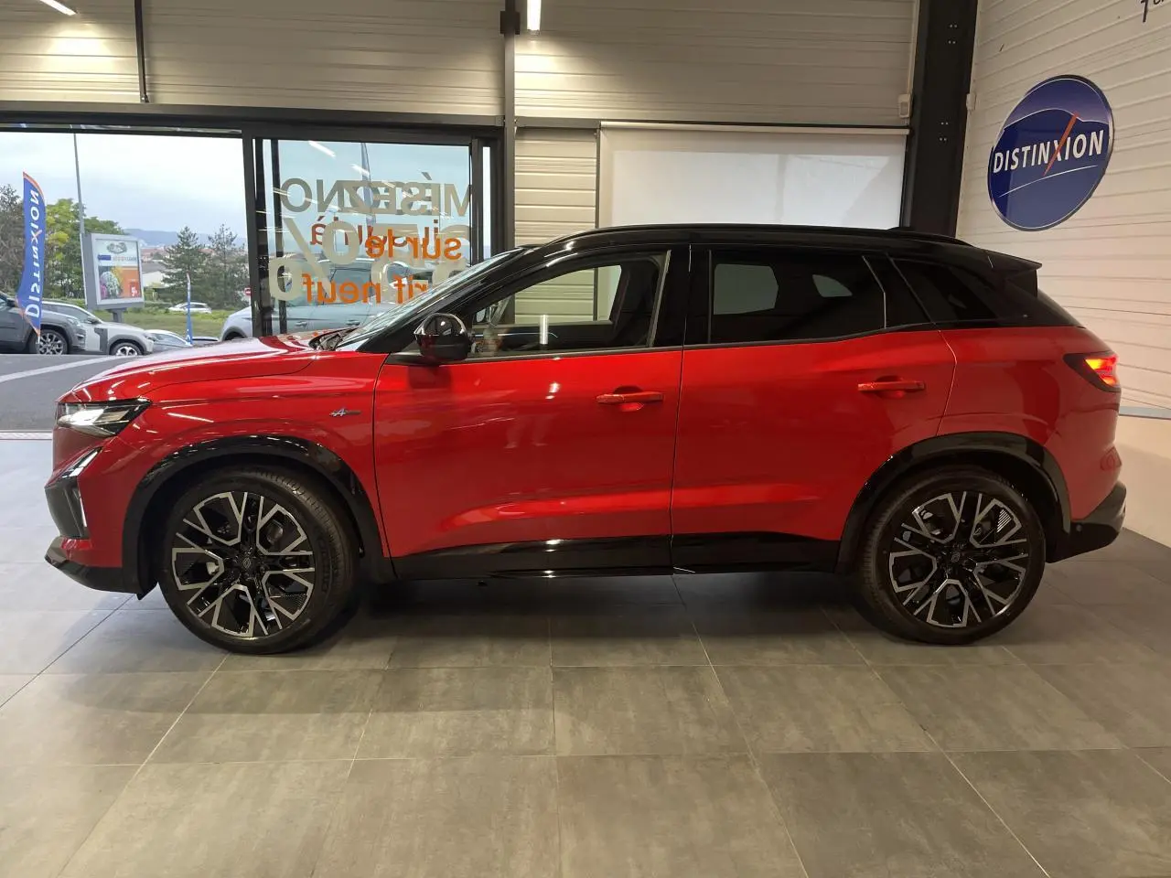 Profil gauche du Renault Austral 2025 rouge métallisé avec toit noir et jantes alliage 20 pouces en intérieur showroom.