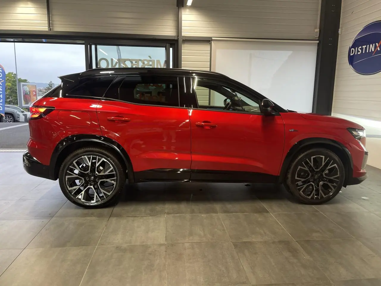 Renault Austral 1.2 E-Tech Hybride rouge métallisé avec toit noir, vue de profil côté gauche en intérieur showroom.