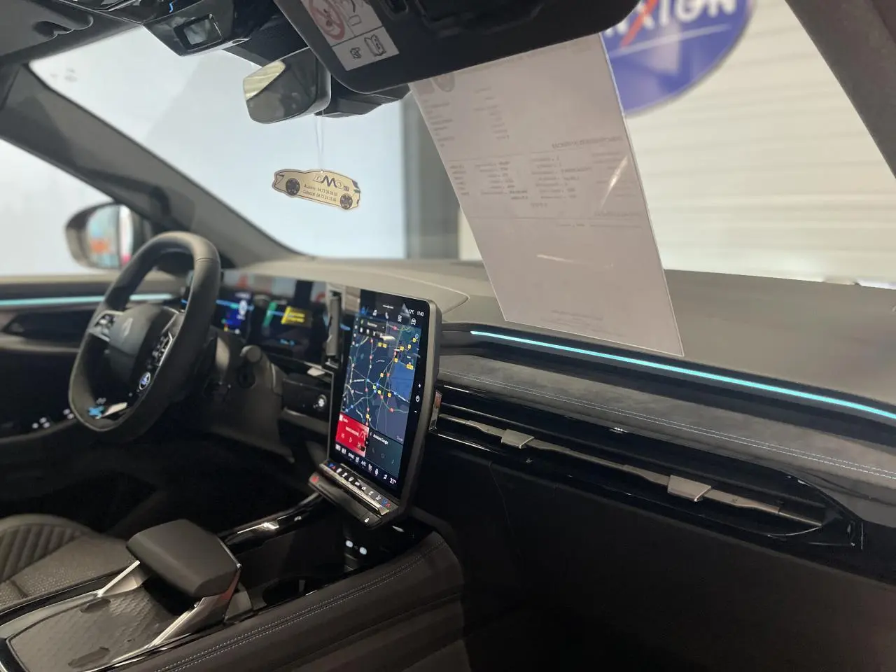 Intérieur Renault Austral 2025 vu côté conducteur, tableau de bord noir avec écran tactile vertical et éclairage bleu.