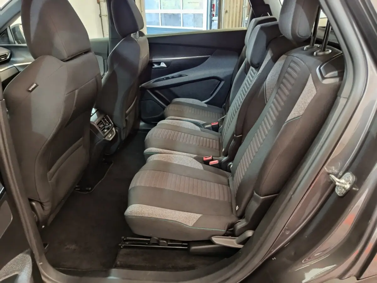 Vue côté droit sur les sièges arrière gris foncé et tissu du Peugeot 5008 2023, avec porte ouverte et habillage intérieur.